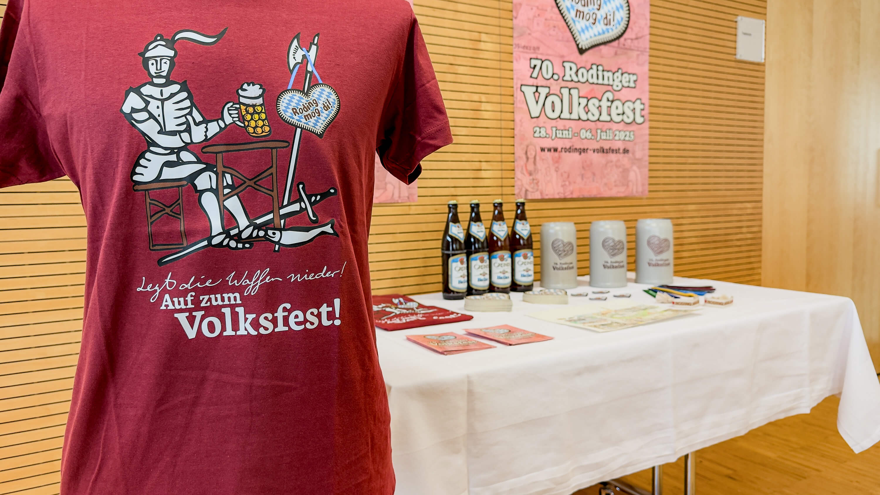 Rotes T-Shirt mit dem Ritter aus dem Stadtwappen der Stadt Roding. Im Hintergrund auf einem Tisch die weiteren Fanartikel.