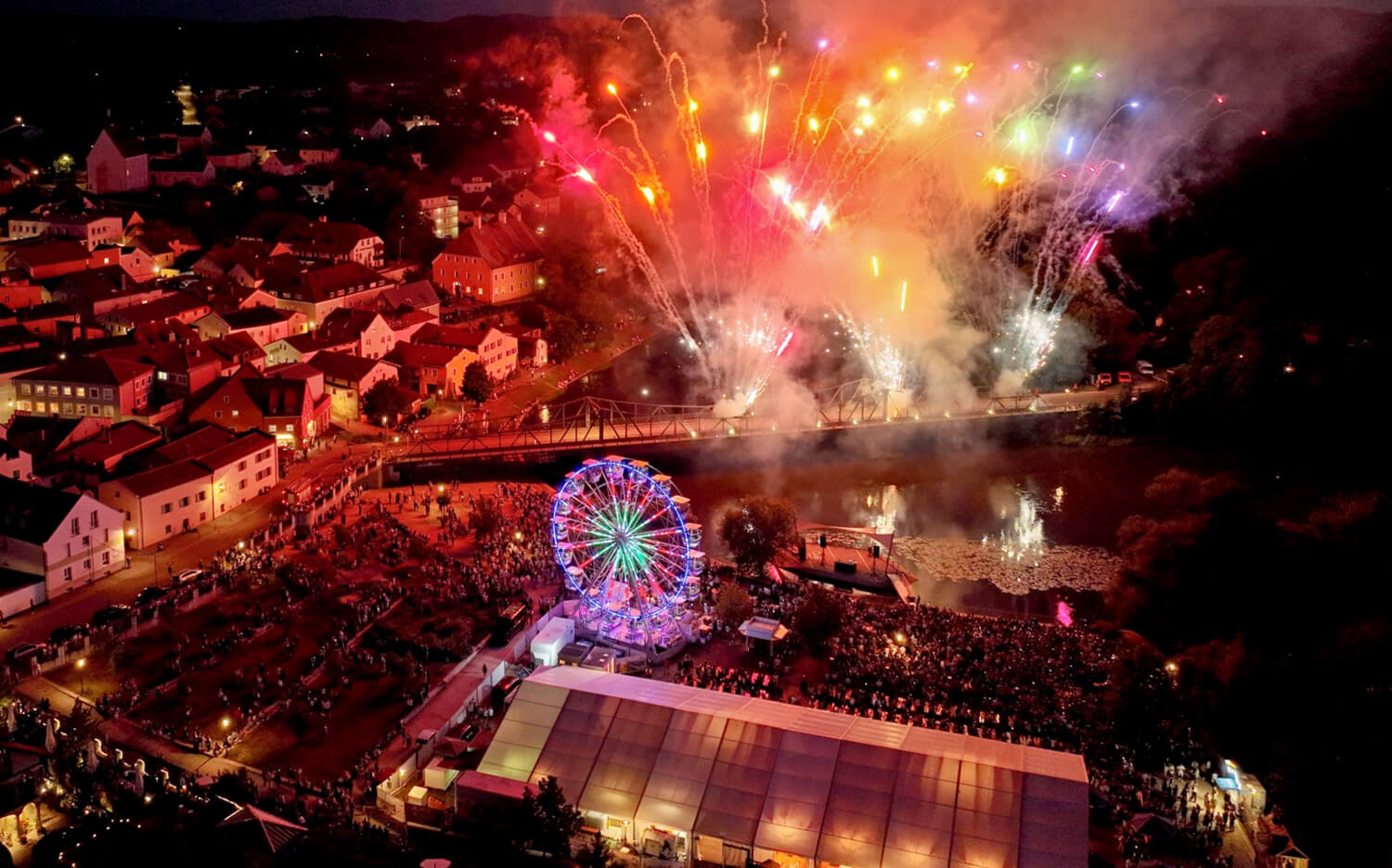 Bunte Lichter leuchten am Abendhimmel über dem Fluss Regen vor dem Festzelt